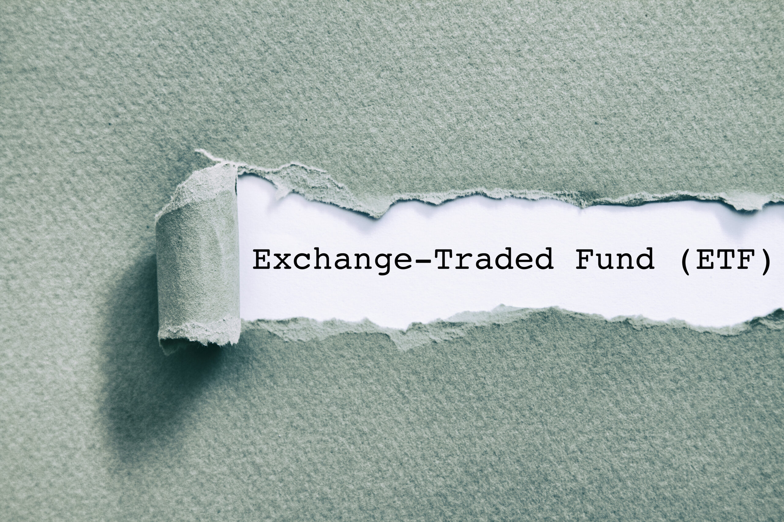 Exchange Traded Fund (ETF) written under torn paper.