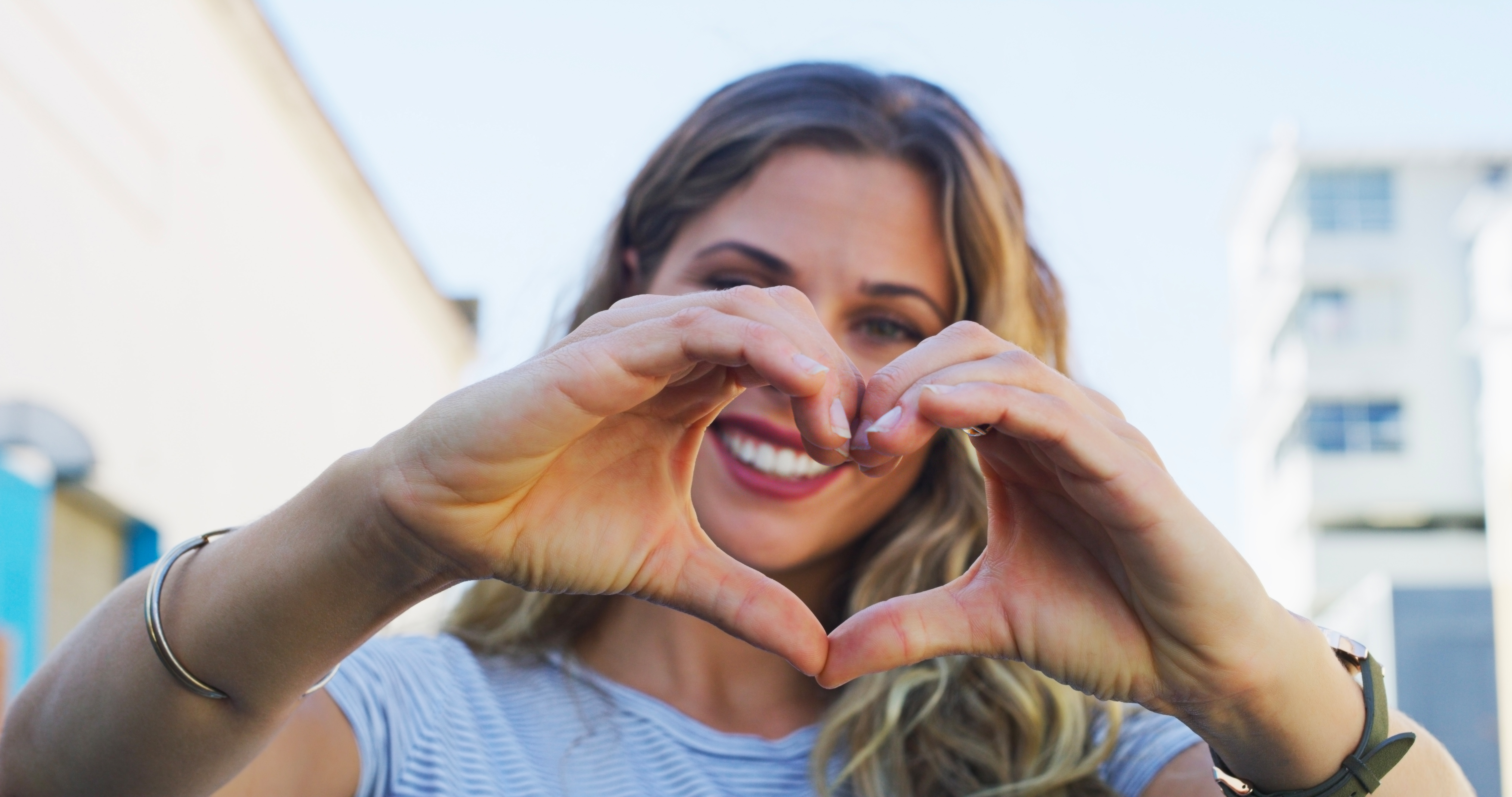 A woman forms a heart with her hands, illustrating the importance of donating and making an impact.